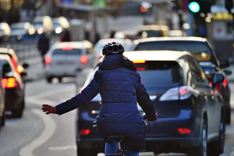 Winter city scene. Woman on bike in traffic